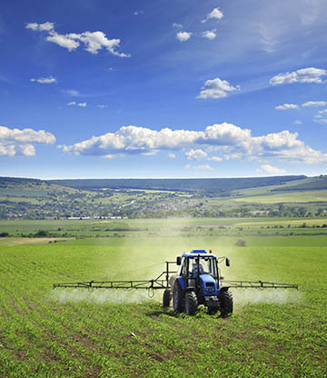 Tractor using hydraulic-powered equipment to spray crops in an agricultural field, highlighting Hydraulic Supply Company's solutions for the agriculture industry