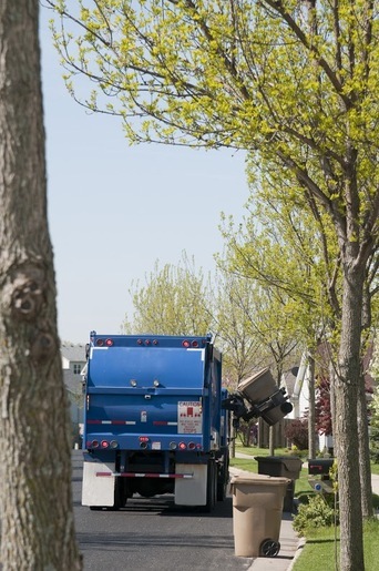 Garbage truck lifting waste bins, representing hydraulic solutions for the waste disposal industry by Hydraulic Supply Company.