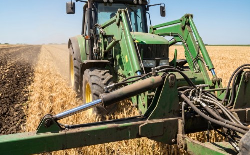 Agricultural tractor with hydraulic lift arm cylinders in a field