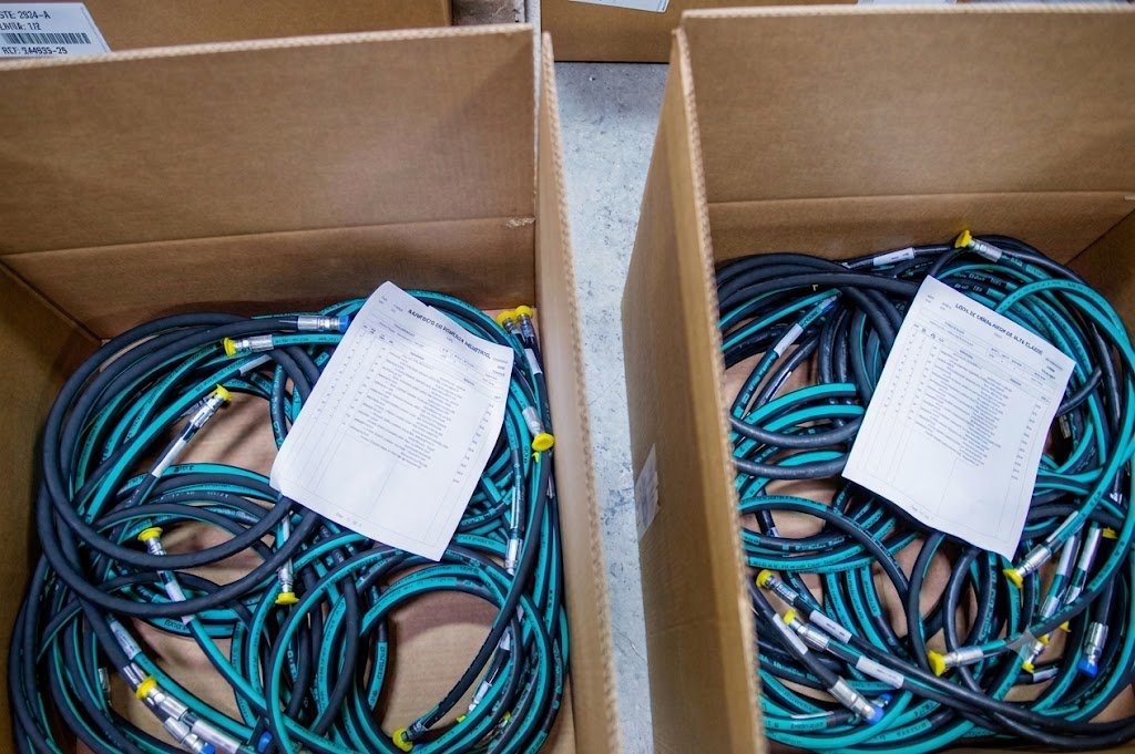 Two boxed hose kits with printed BOM sheets and labeled, coiled hose assemblies ready for shipment